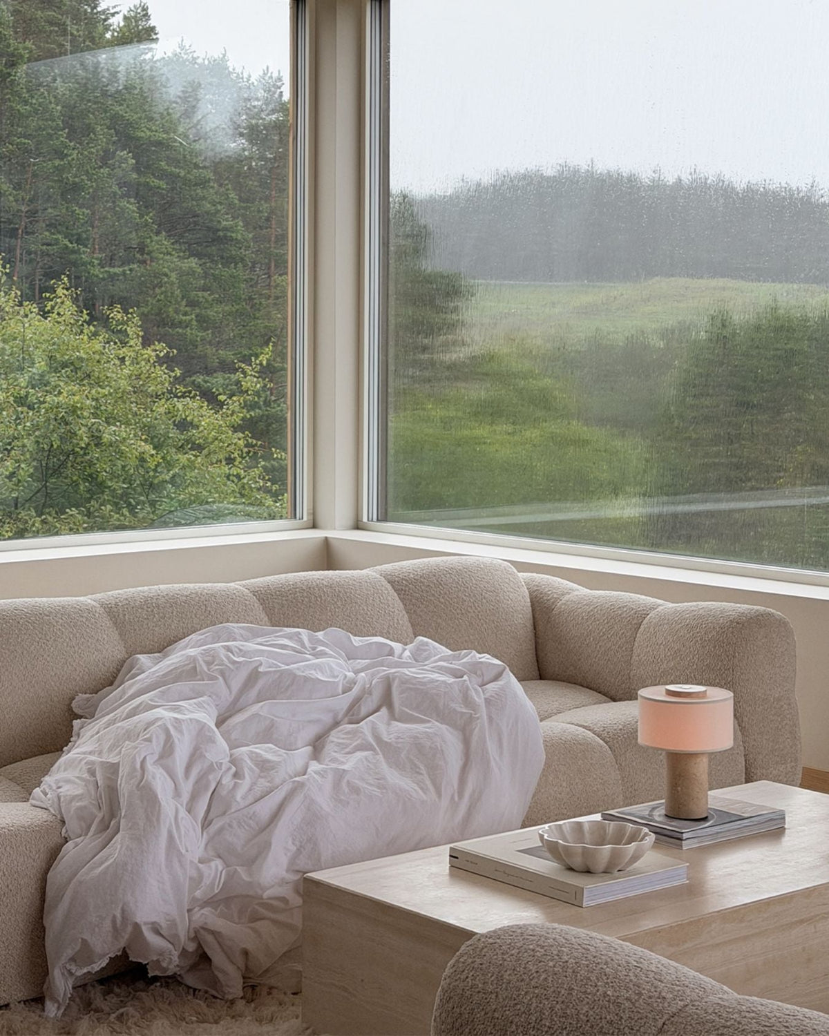 Oriel Travertine Portable Lamp beside a bed beneath a large window
