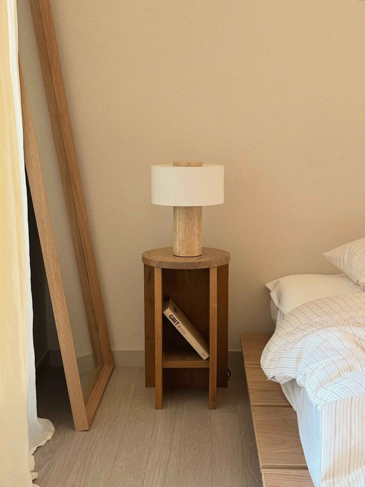 Oriel Travertine Table Lamp on a tall stool beside a mirror