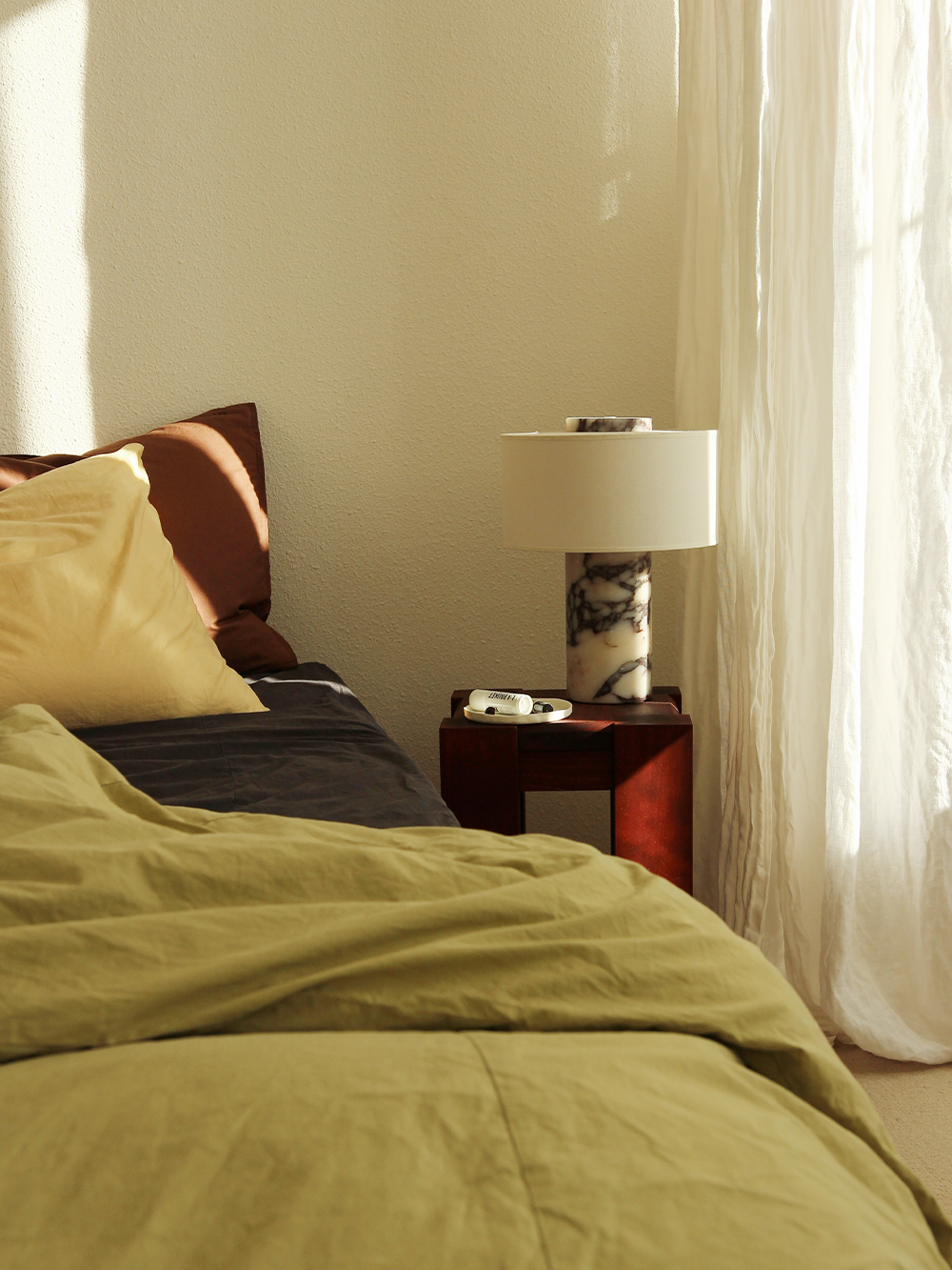 Oriel Calacatta Marble Table Lamp on a bedside table beside green bedding